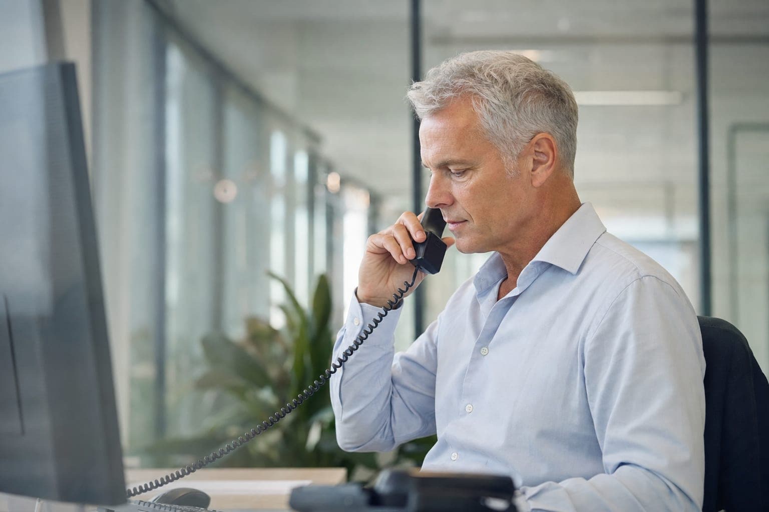 Mitarbeiterin im Telefonat am Schreibtisch, bereit für Ihr Erstgespräch
